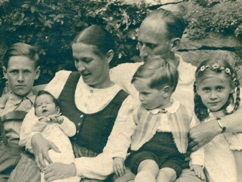 Ein altes schwarz-weißes Bild zeigt eine Familie. In der Mitte steht Leni Mahnert-Lueg, eine Frau, die mit ihrer Stiftung viel Gutes getan hat. Die Familie strahlt Zusammenhalt und Tradition aus.