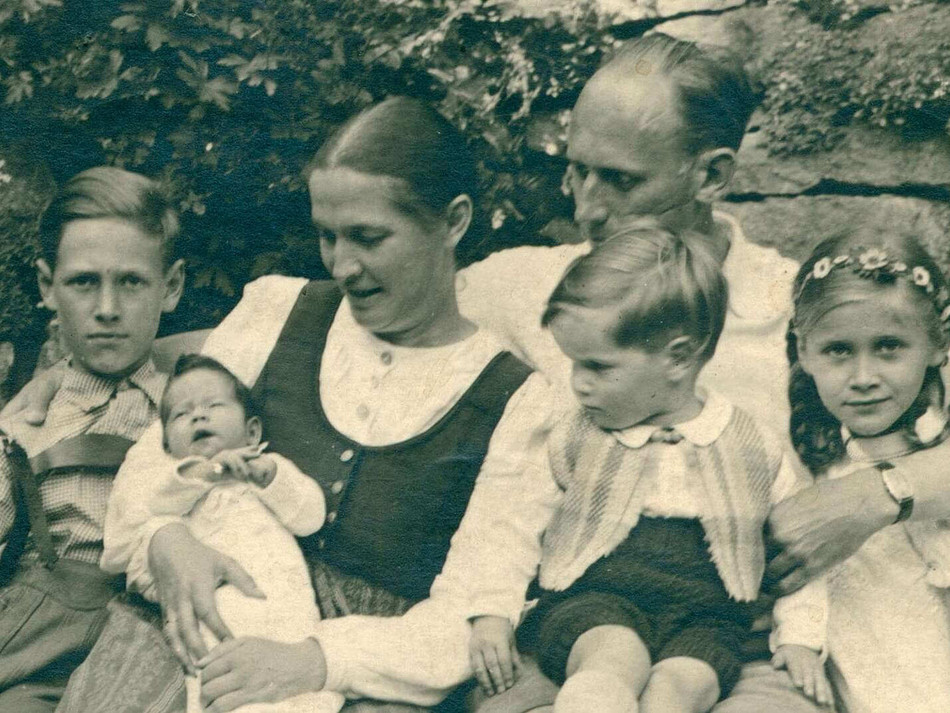 Ein altes schwarz-weißes Bild zeigt eine Familie. In der Mitte steht Leni Mahnert-Lueg, eine Frau, die mit ihrer Stiftung viel Gutes getan hat. Die Familie strahlt Zusammenhalt und Tradition aus.