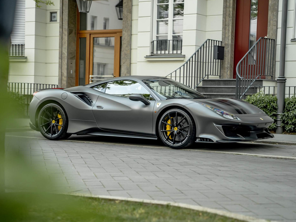 Ein grauer Ferrari, geparkt vor einem schönem Gebäude.